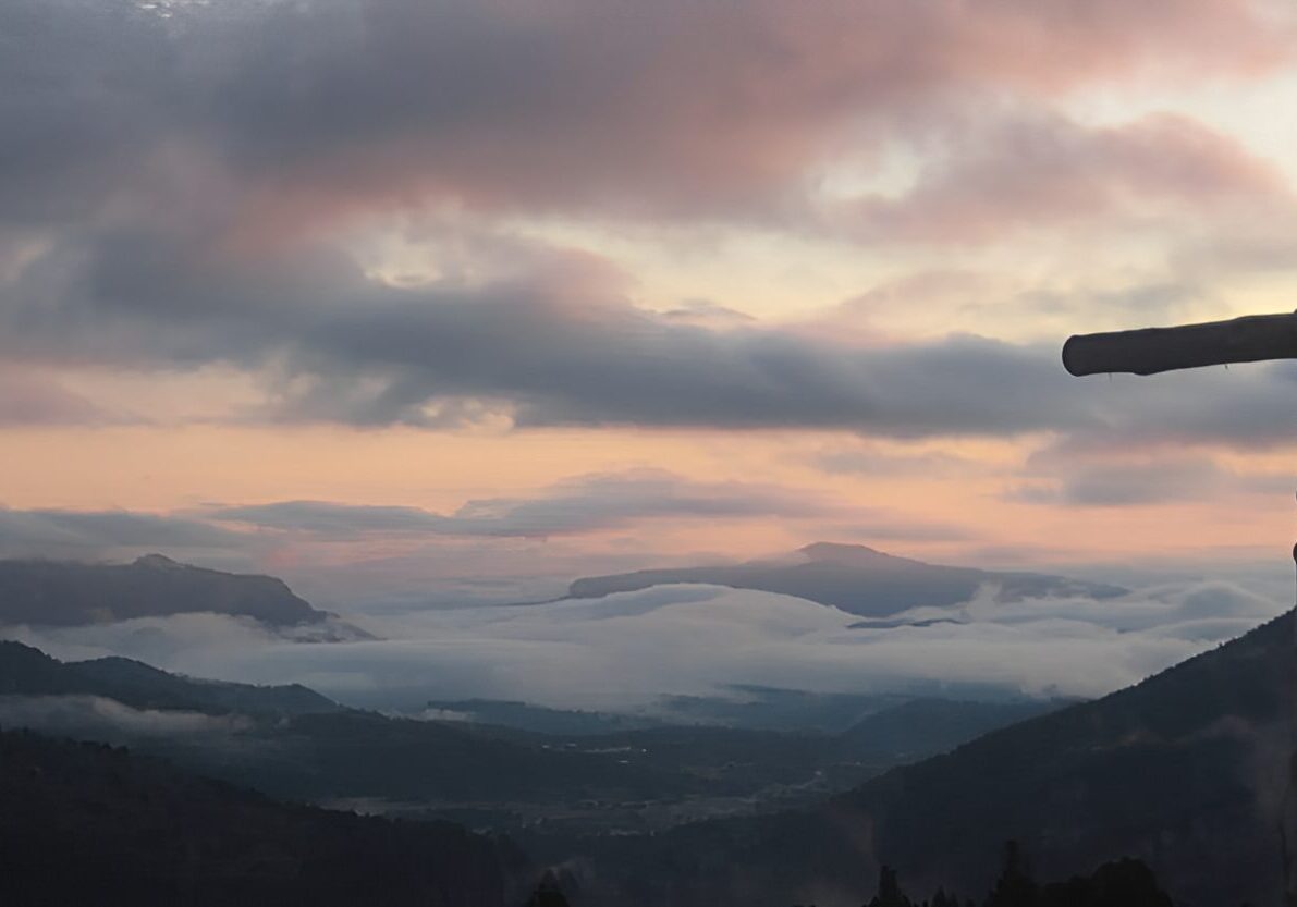 Mountain sunrise with cross in foreground.